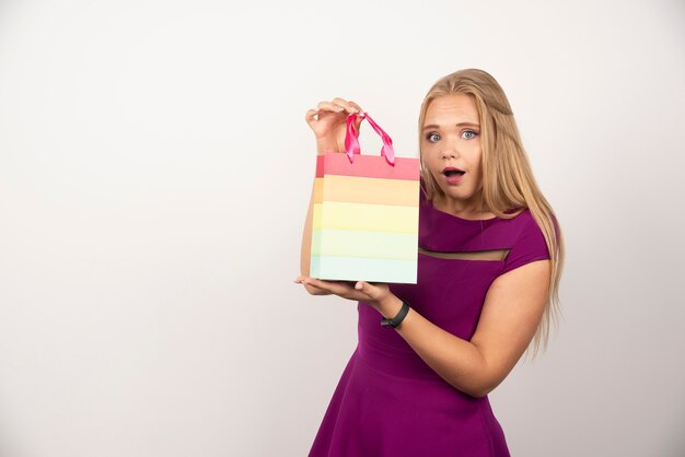 Hübsche Frau, die Geschenktüte mit glücklichem Ausdruck hält.