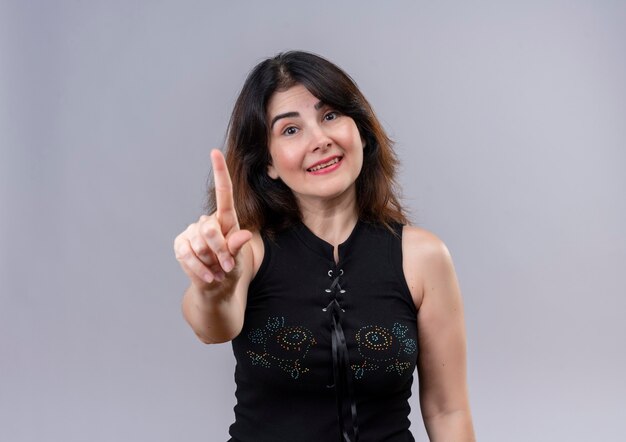 Hübsche Frau, die lächelnde schwarze Bluse trägt, die Verbot mit Zeigefinger zeigt