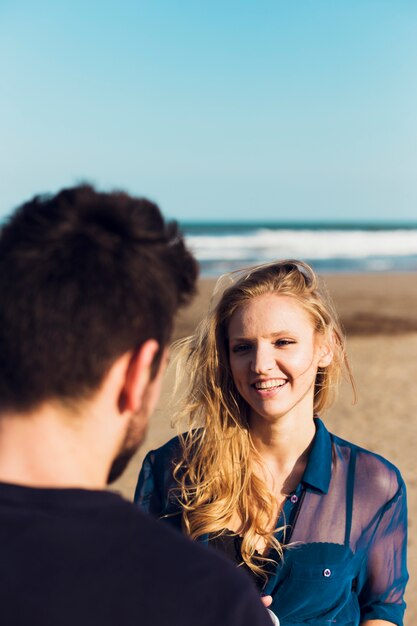 Hübsche Frau, die mit Mann auf Strand spricht