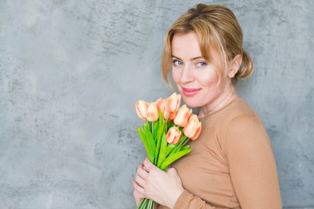 Hübsche Frau, die mit Tulpenblumenstrauß steht