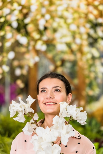 Hübsche Frau, die mit weißen Blumen steht