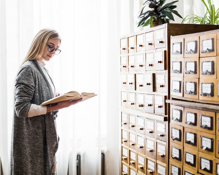 Kostenlose Foto hübsche frau, die nahe bibliotheksfenster liest