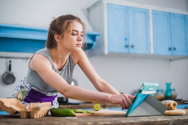 Hübsche Frau, die Rezept vom Internet wählt