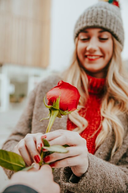 Hübsche Frau, die rote Rose nimmt