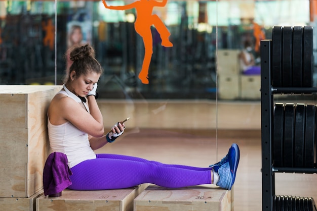 Hübsche Frau, die Smartphone während des Trainings verwendet