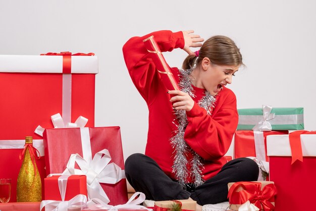 hübsche Frau, die um Weihnachtsgeschenke auf Weiß sitzt