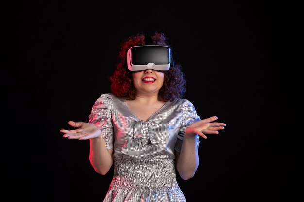 Hübsche Frau, die Virtual-Reality-Headset auf dunkler Oberfläche trägt
