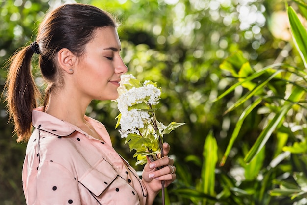 Hübsche Frau, die weiße Blumen riecht