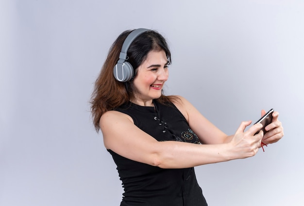 Hübsche Frau in der schwarzen Bluse, die Selfie im Kopfhörer macht