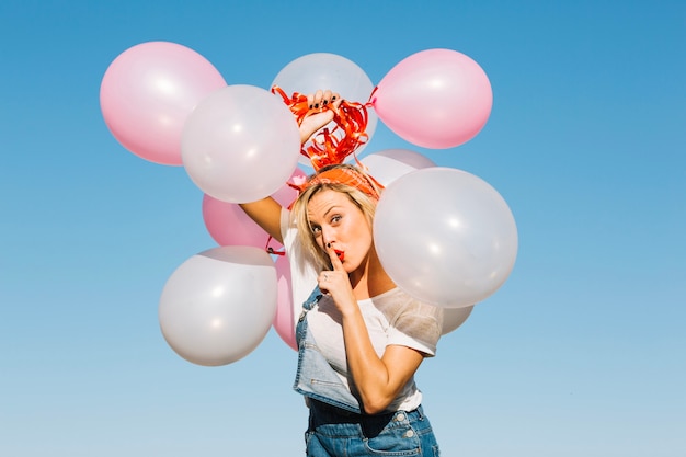 Hübsche Frau mit den Ballonen, die Ruhe gestikulieren