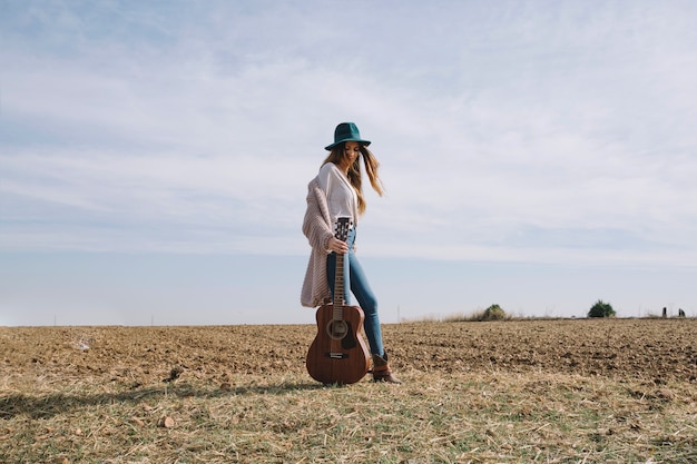 Hübsche Frau mit Gitarre auf dem Gebiet