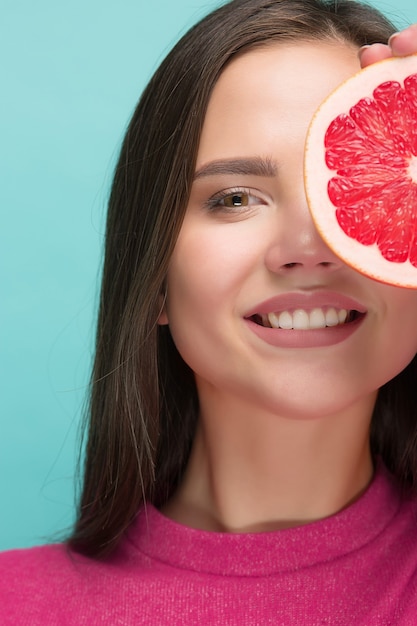 Hübsche Frau mit köstlicher Grapefruit in ihren Armen