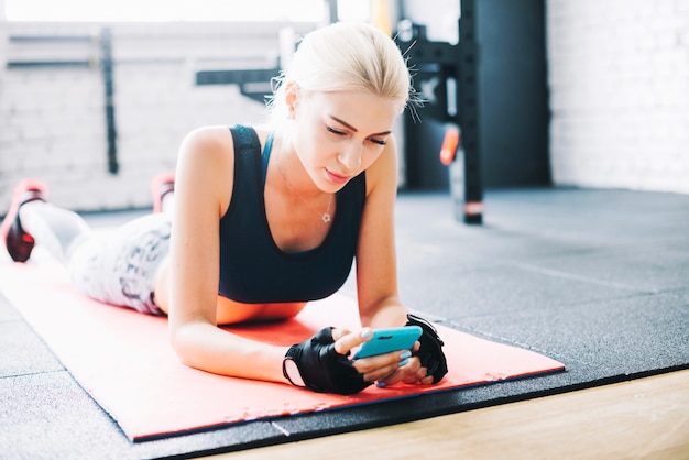 Hübsche Frau mit Smartphone während des Trainings