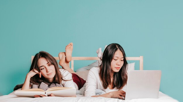 Hübsche Frauen, die auf Bett studieren