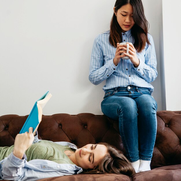 Hübsche Frauen, die auf Couch sich entspannen