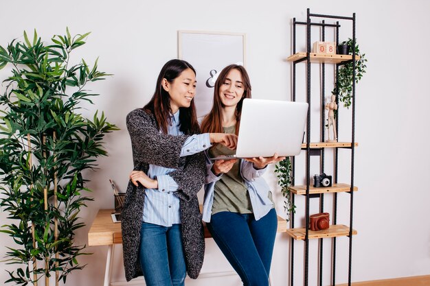 Hübsche gemischtrassige Frauen, die am Laptop coworking sind