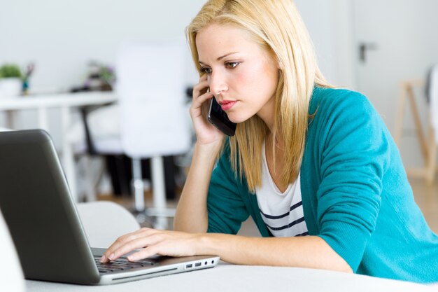 Hübsche junge Frau arbeitet mit Laptop zu Hause.