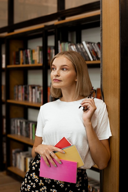 Hübsche junge Frau, die an der Bibliothek aufwirft