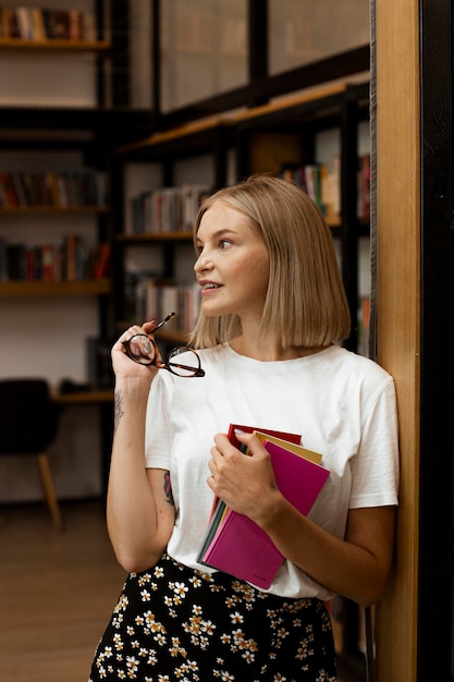 Hübsche junge Frau, die an der Bibliothek aufwirft