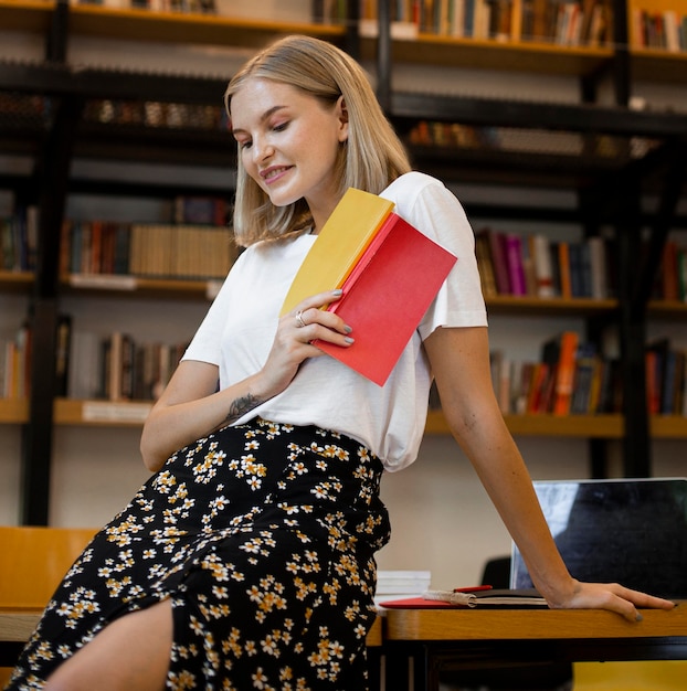 Hübsche junge Frau, die an der Bibliothek aufwirft