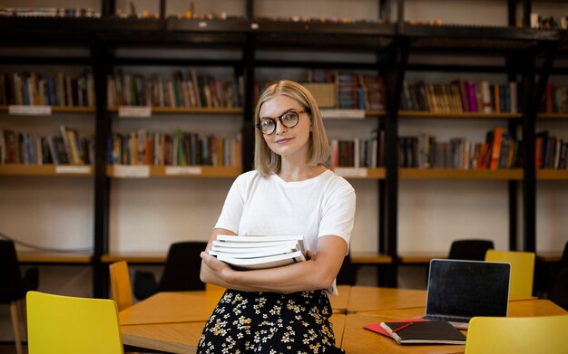 Hübsche junge Frau, die an der Bibliothek aufwirft