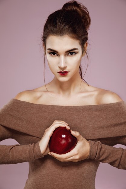 Hübsche junge Frau, die brutal roten Apfel in den Händen hält.