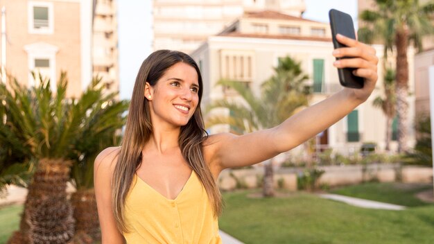 Hübsche junge Frau, die ein Selfie im Freien nimmt