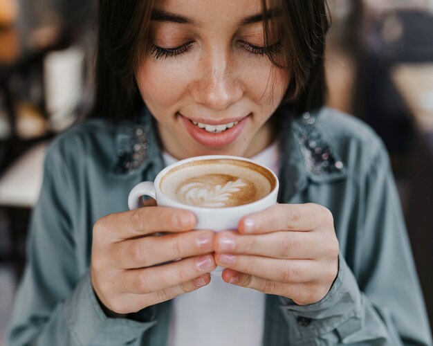 Hübsche junge Frau, die eine Kaffeetasse genießt