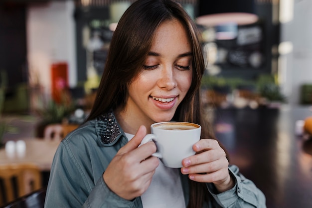 Hübsche junge Frau, die eine Kaffeetasse genießt
