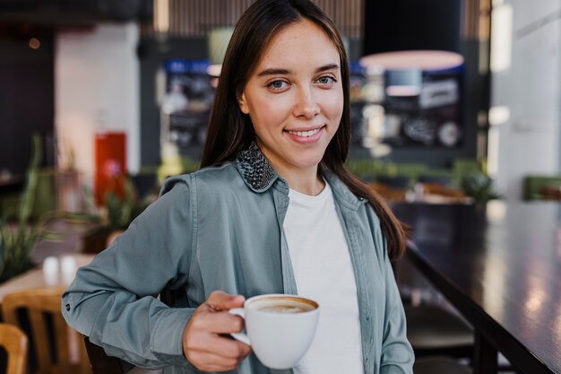 Kostenloses Foto hübsche junge frau, die eine kaffeetasse genießt