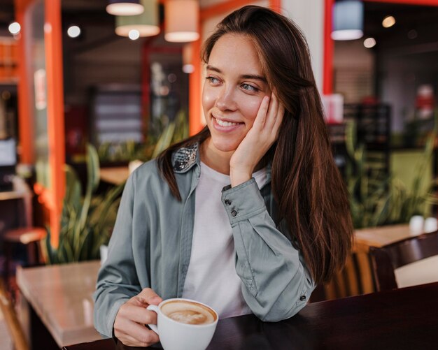 Hübsche junge Frau, die eine Kaffeetasse genießt