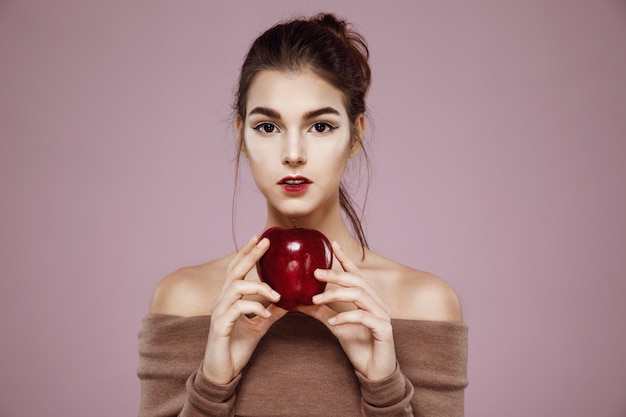 Hübsche junge frau, die roten apfel in den händen hält.