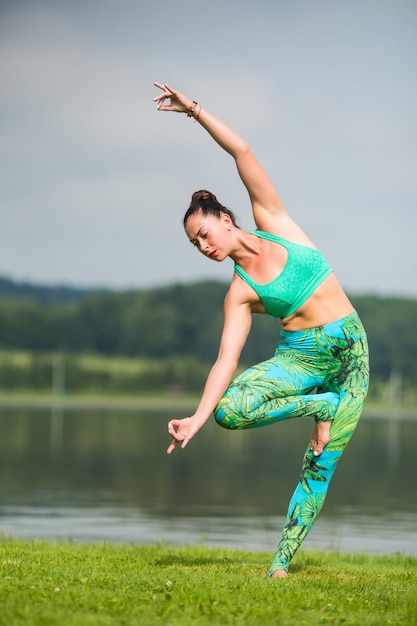 Hübsche junge frau, die yogaübungen im park macht