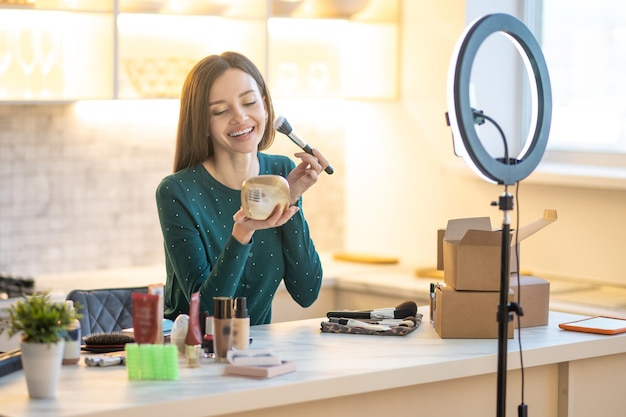 Hübsche junge Frau im grünen Kleid, das Make-up-Tipps zeigt