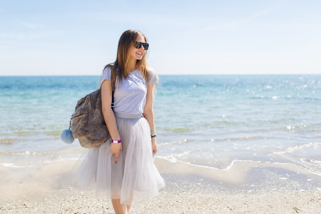 Hübsche junge Frau mit Tasche steht nahe Meer