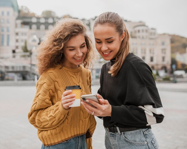Hübsche junge Mädchen, die zusammen ein Telefon überprüfen