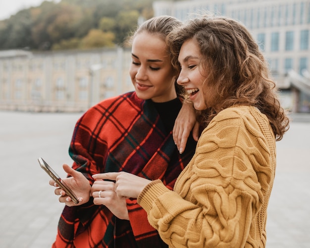 Hübsche junge Mädchen, die zusammen ein Telefon überprüfen