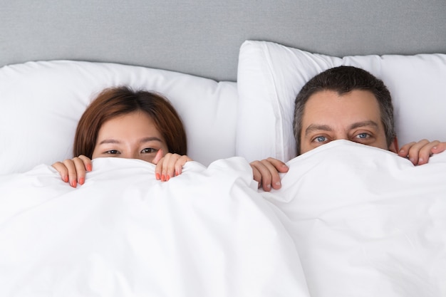 Hübsche junge Paar versteckt sich hinter Duvet