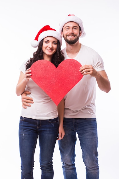 Hübsche junge Santa paar Freunde Mann Frau Weihnachtsmütze halten großes leeres leeres Herz isoliert auf weißem Hintergrund Studio. Frohes neues Jahr Feier Frohe Feiertage Konzept