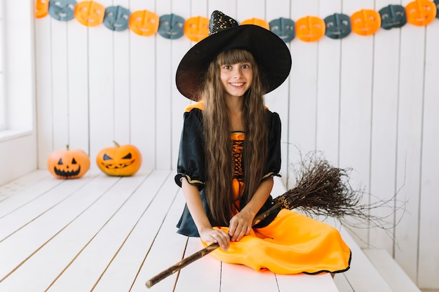 Hübsche kleine Hexe mit Besen auf Halloween-Party