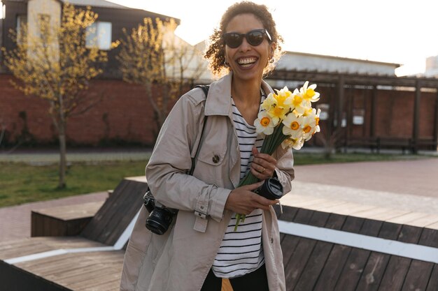 Hübsche lächelnde Frau auf der Straße mit Blumen