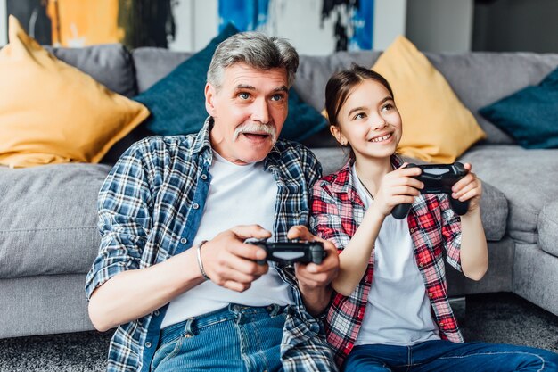 Hübsche lächelnde Tochter, die mit Großvater Konsole spielt!