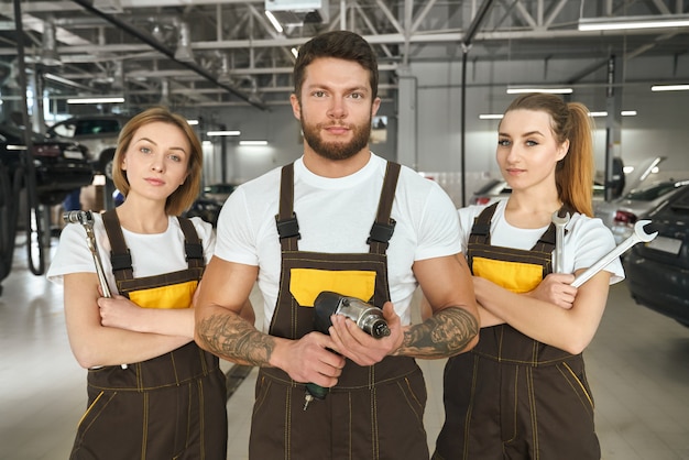 Kostenloses Foto hübsche mann- und frauenmechaniker des autoservice posieren.