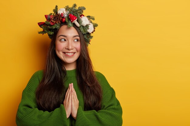 Hübsche und junge Frau, die Weihnachtskranz auf ihrem Kopf trägt