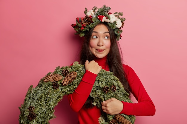 Hübsche und junge Frau, die Weihnachtskranz auf ihrem Kopf trägt