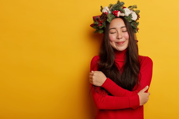 Hübsche und junge Frau, die Weihnachtskranz auf ihrem Kopf trägt