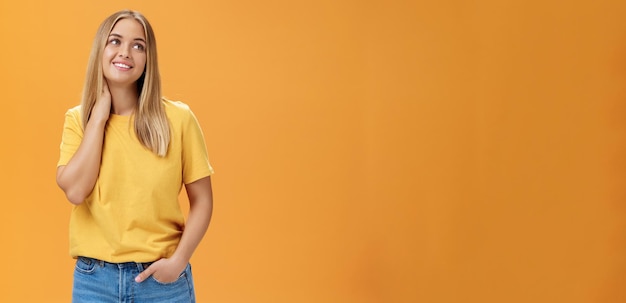 Kostenloses Foto hübsche und zarte süße europäische unabhängige freiberuflerin im gelben t-shirt, das den hals berührt