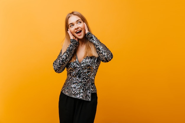 Hübsche wohlgeformte Frau, die mit glücklichem Lächeln aufwirft. Innenporträt der niedlichen europäischen Frau im eleganten Partyoutfit.