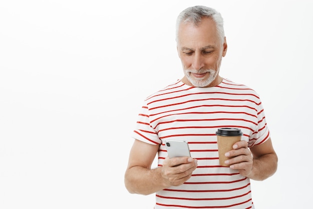 Hübscher älterer Mann, Vater, der Smartphone betrachtet und Kaffee trinkt