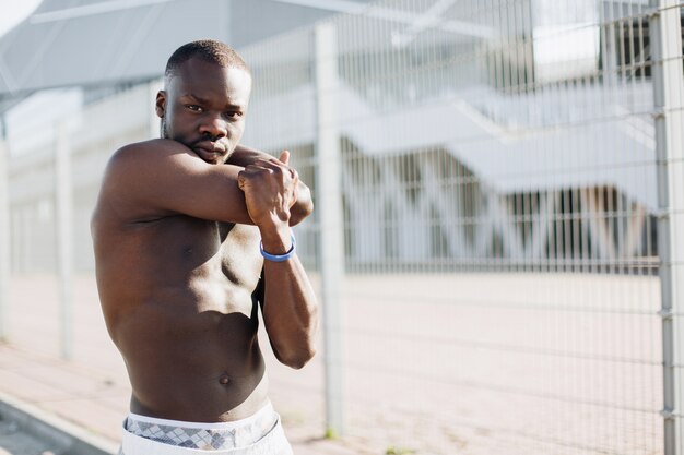 Hübscher Afroamerikanermann dehnt vor einem Training draußen aus